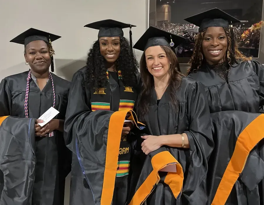 Several Herzing University nursing graduates smiling at graduation ceremony in black gowns